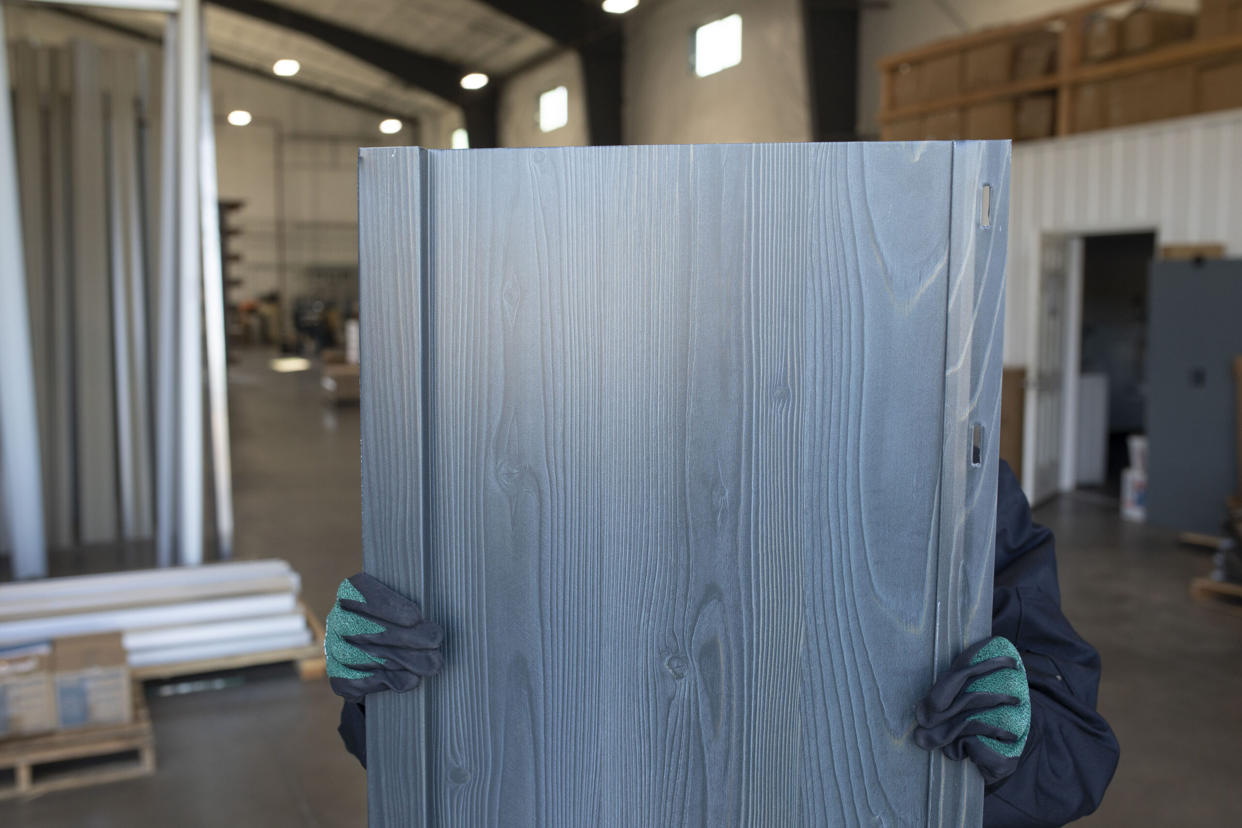 An employee of Metal America holds up a steel siding wall panel