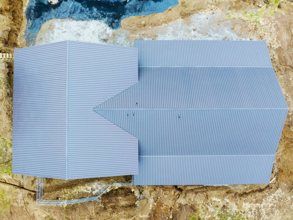 Exposed fastener roofing panels are shown on a horse barn