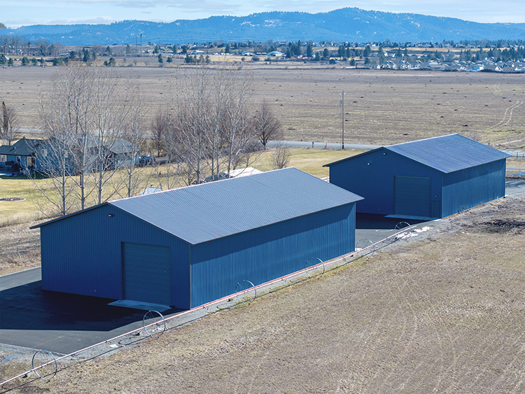 Two blue pole barns with matching blue metal roofs
