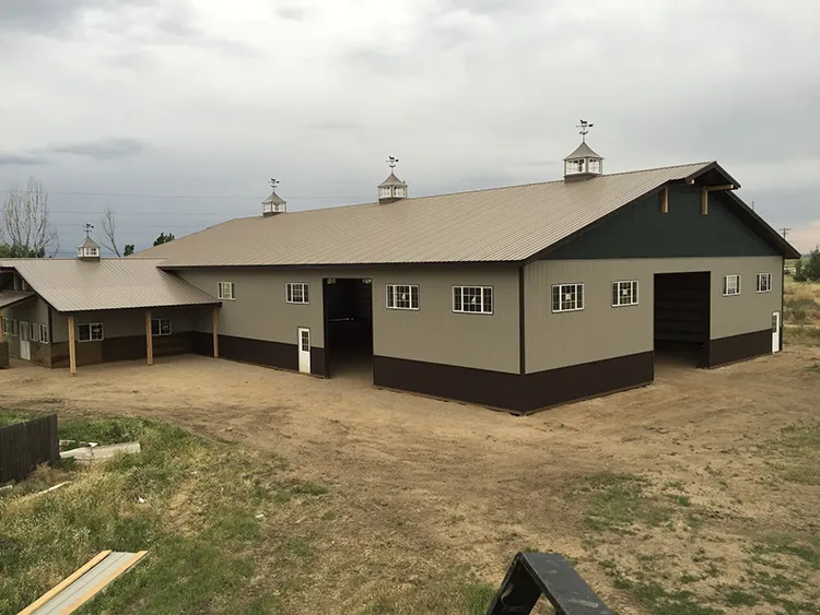 A farm building with a metal roof that is brown in color