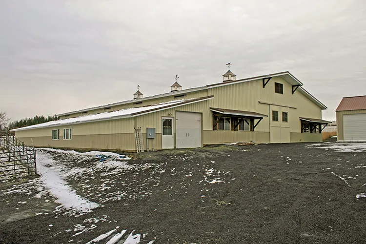 A yellow farm building with a metal roof and corrugated metal siding
