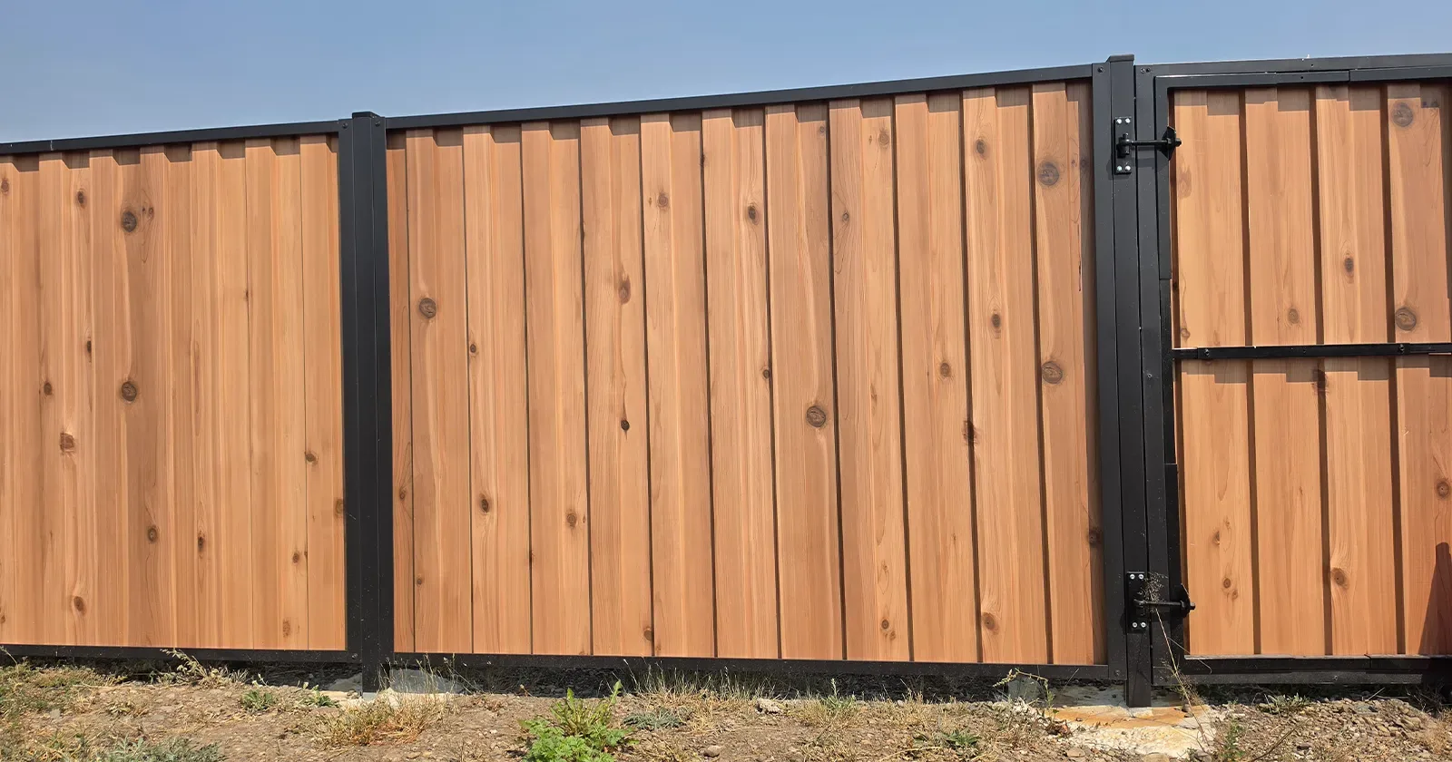 A steel wood look fence panel being installed, the fix for the question are wood fences a fire hazard