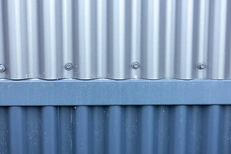 Closeup of corrugated steel siding on a building, a non combustible wall that helps protect your home from wildfire