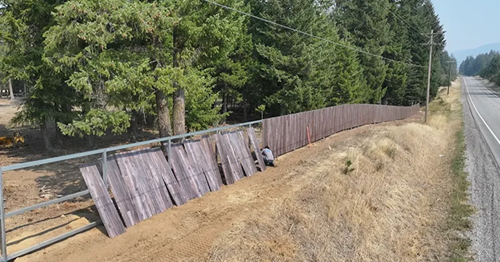 A steel fence being installed next to wood fencing, showing the best fireproof fencing choice of the two
