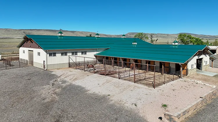 A cattle barn with a green steel roof, a common use for exposed fastener steel roof panels