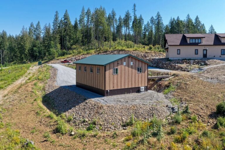 Aerial view of a Smooth Cedar and Fern Green metal shop on a hillside lot